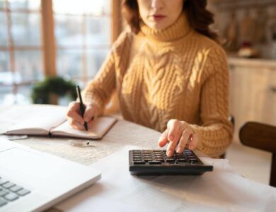 Dark-haired young woman in sweater making calculations