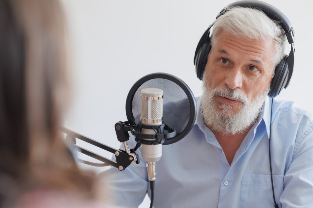 older man with gray hair and female guest in a recording studio are recording podcast