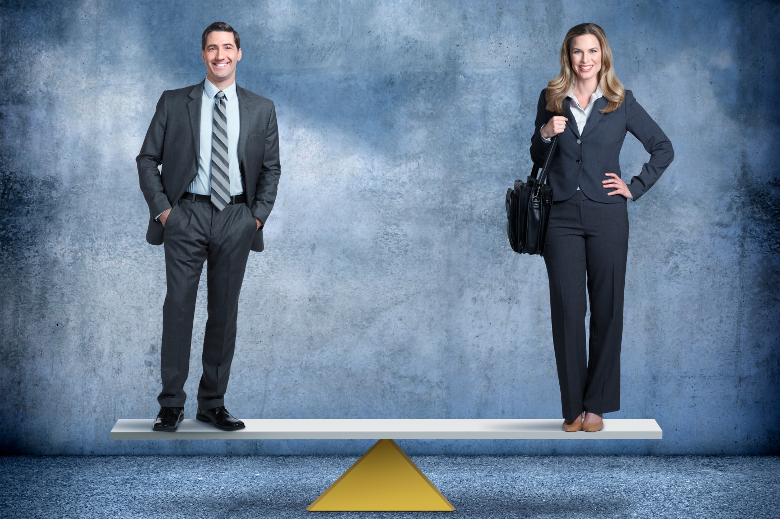 A man and a woman in business attire stand on opposite ends of a balanced seesaw, symbolizing equiparação salarial in the workplace. The background is a textured blue-gray wall and floor.
