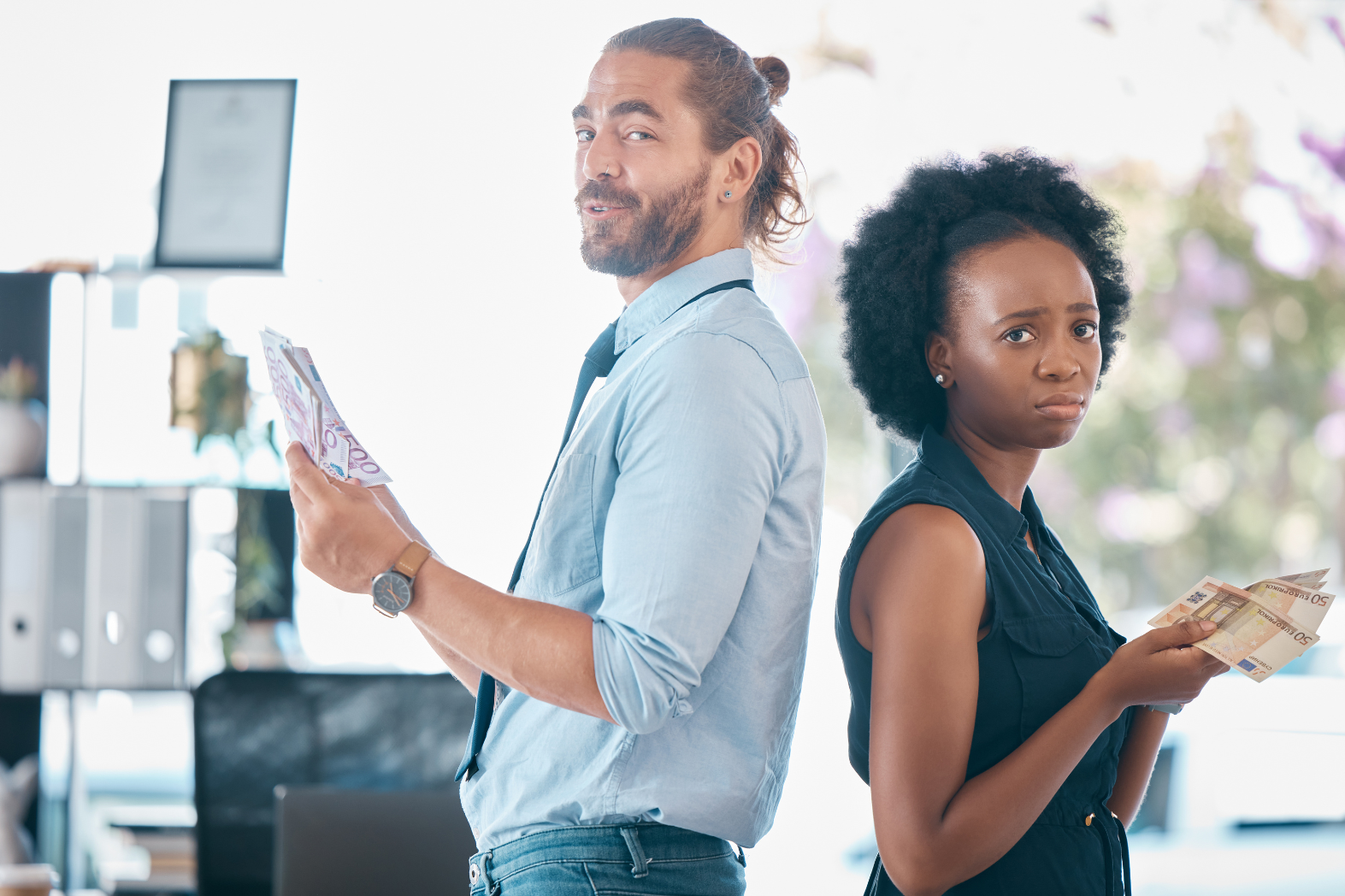 Um homem e uma mulher estão lado a lado em um escritório, cada um segurando dinheiro. O homem parece feliz com mais dinheiro, enquanto a mulher parece infeliz com menos notas, destacando a importância de entender os requisitos para equiparação salarial.